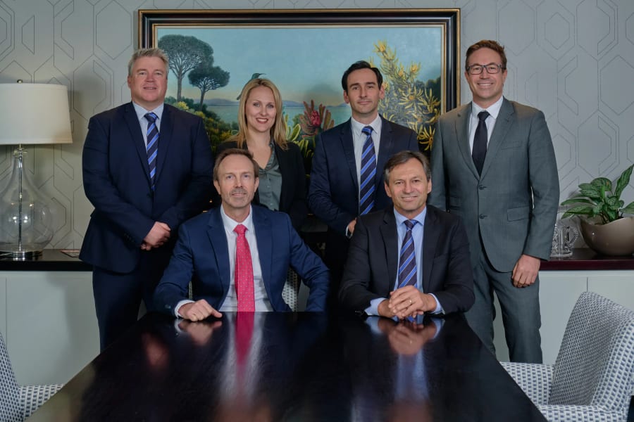 A management team photographed together around the boardroom table, Claremont