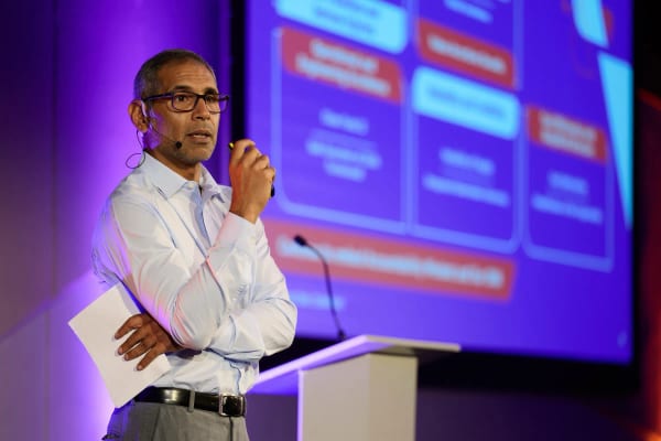 Conference presenter on stage beside a projected slide, Cape Town