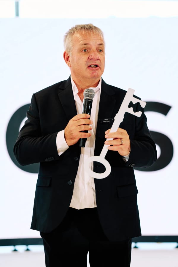 Host holding the ceremonial key during the opening address at a corporate office opening, Cape Town