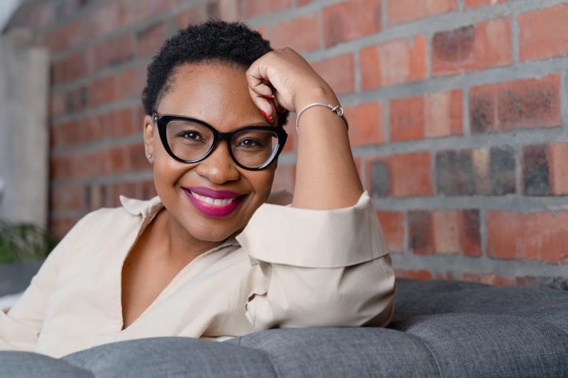 Personal branding portrait, Cape Town, a professional relaxed on a sofa against a brick wall