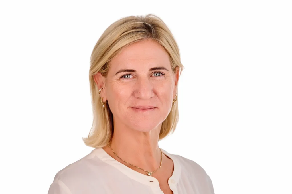 A relaxed, confident business portrait of a professional woman in a white shirt. An example of the 'Executive Standard' studio package by Jürgen's Photography, featuring natural expressions and studio lighting.