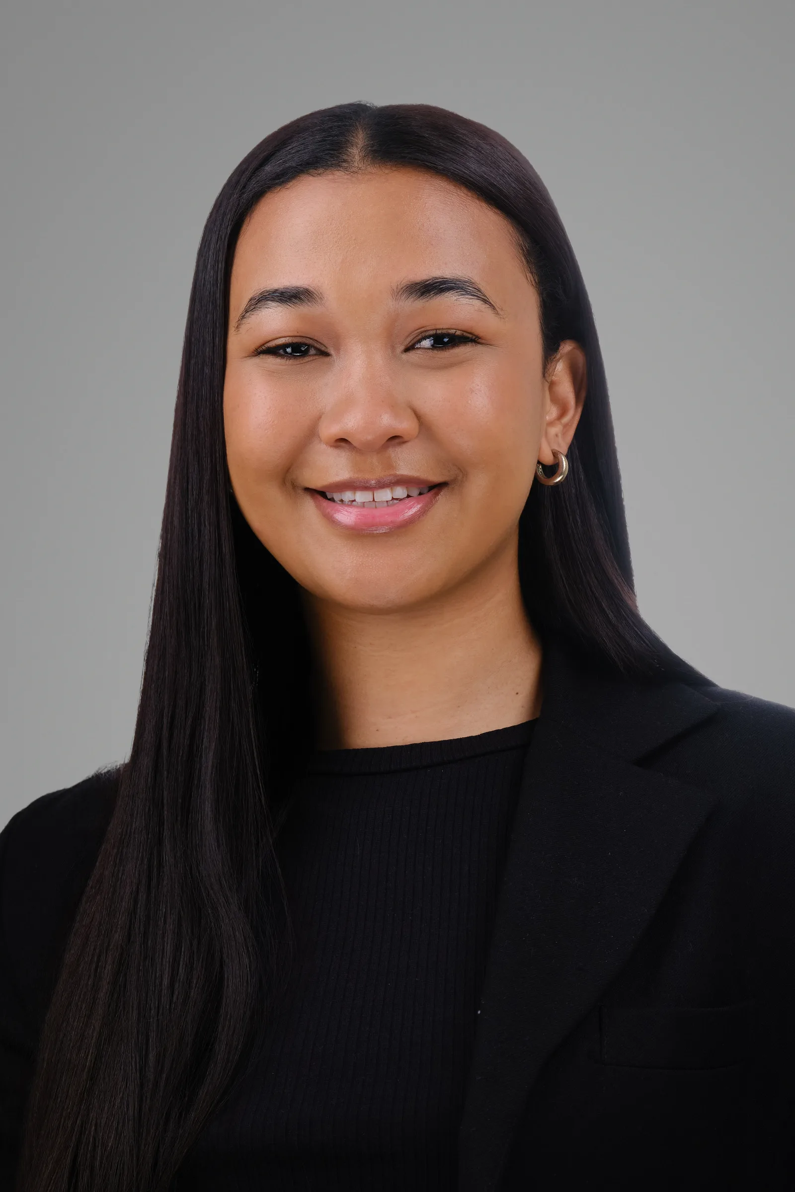 Corporate headshot of a LevelUp HCS team member in a black blazer, grey background, Cape Town