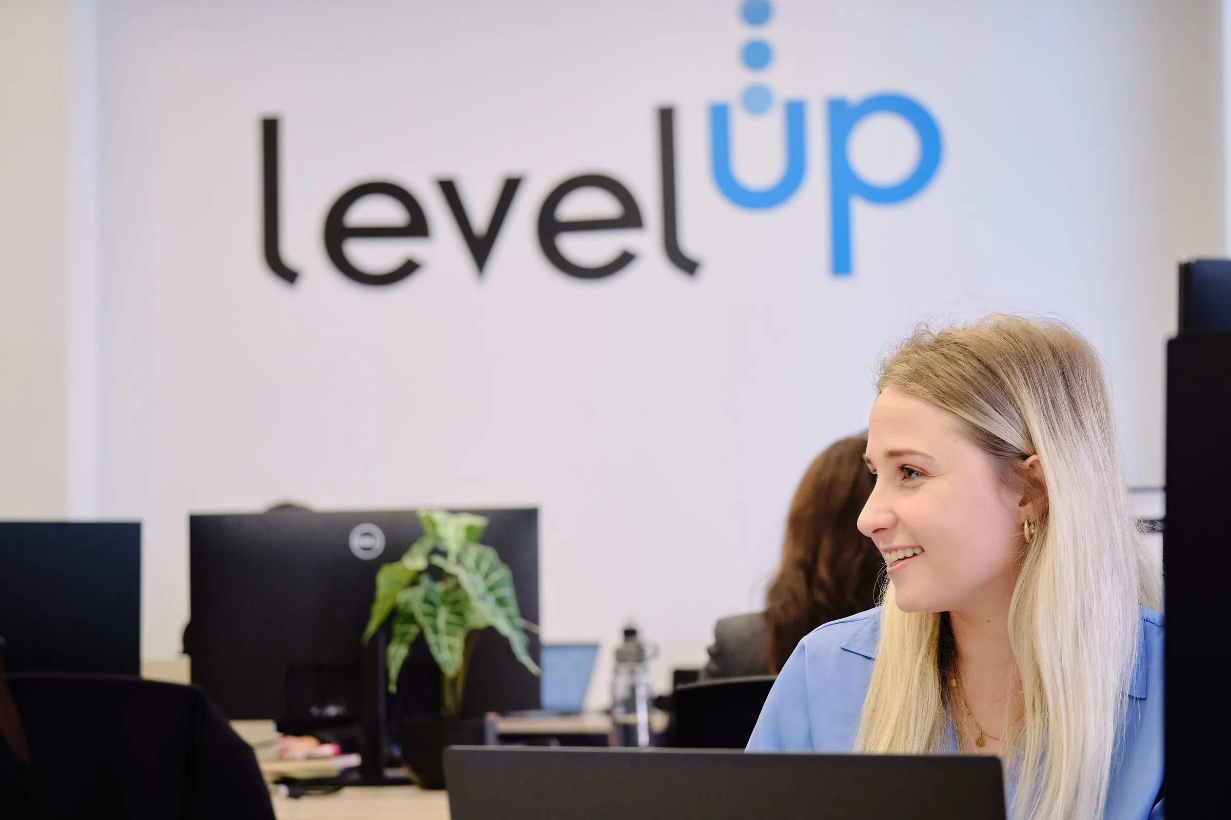 LevelUp HCS team member at her workstation with the LevelUp logo on the wall behind her, Cape Town office