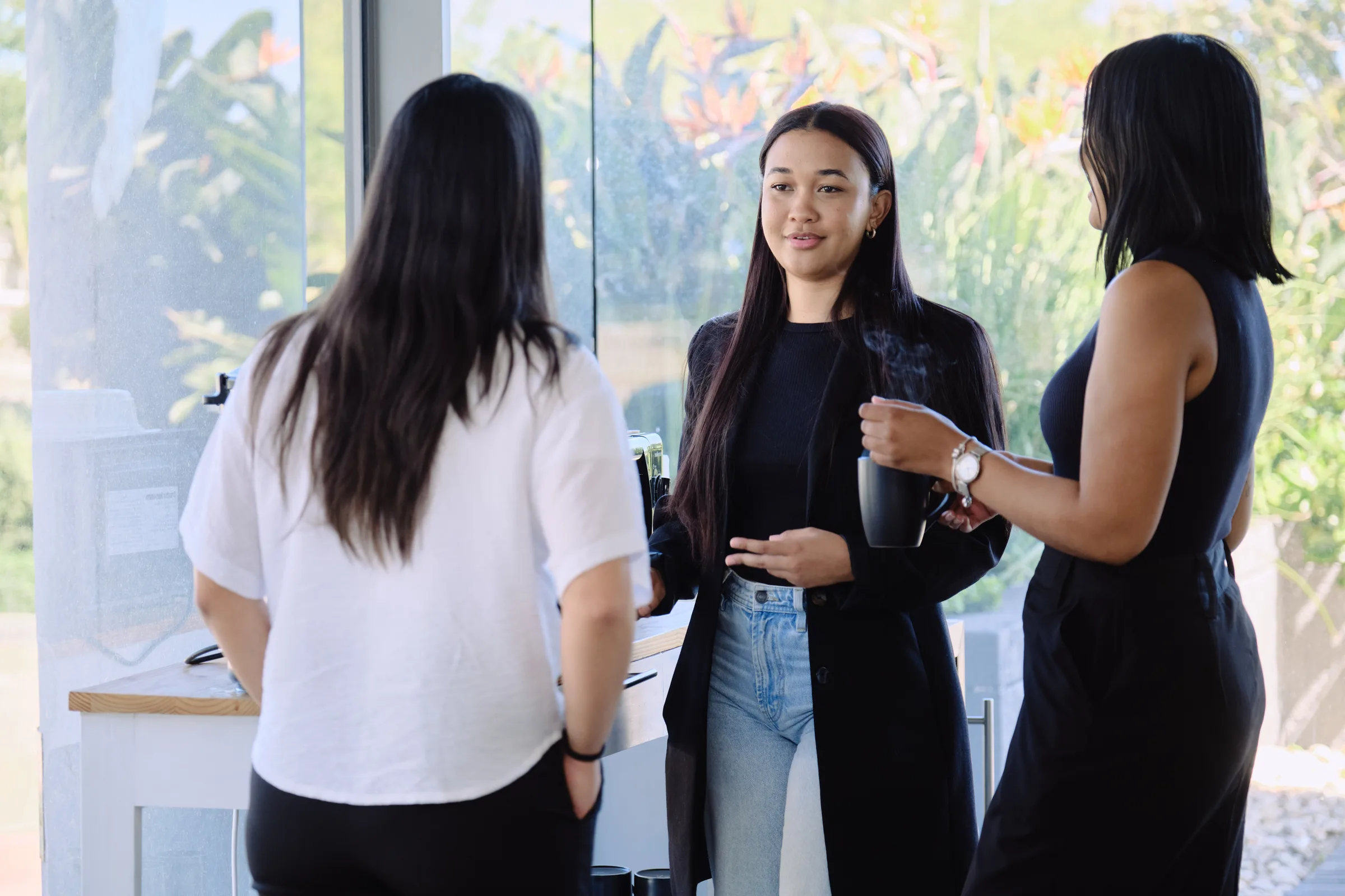 Three LevelUp HCS team members in conversation near the windows of their Cape Town offices