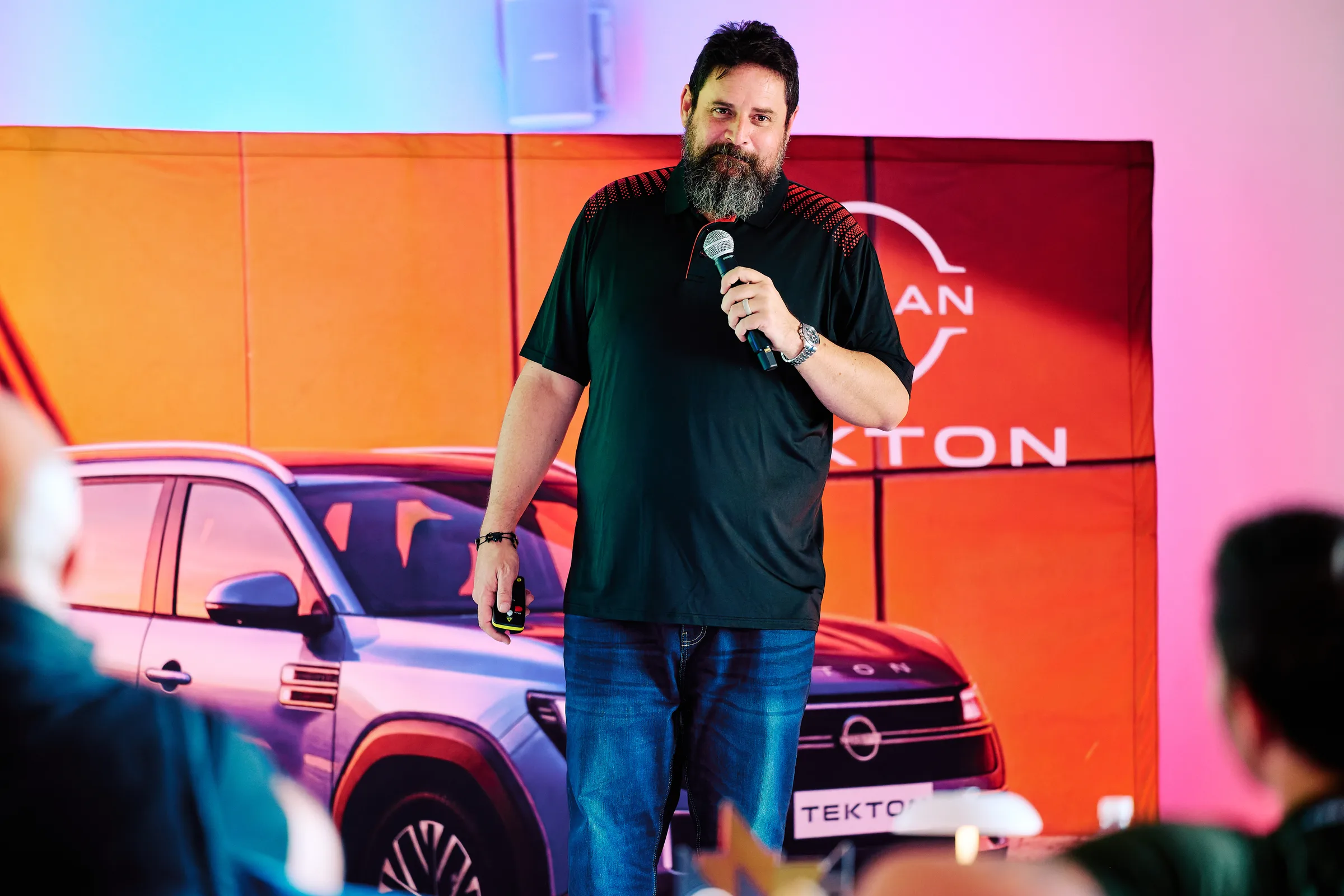 Presenter on stage against the lit screen with a vehicle beside him, launch presentation, Hazendal Wine Estate, Stellenbosch