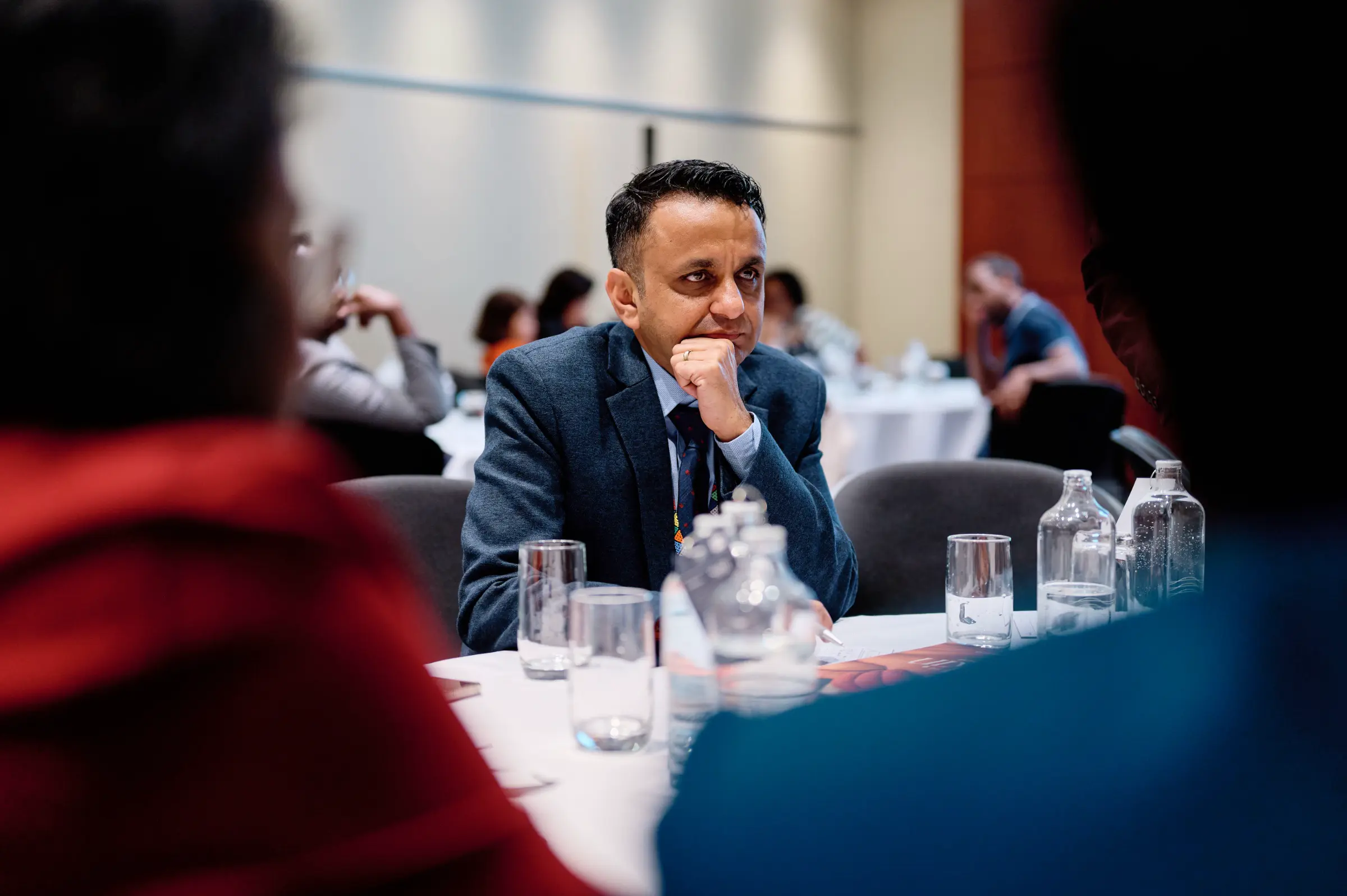 A candid shot of a delegate listening intently during a conference session, capturing the atmosphere of the event.
